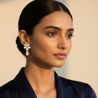 Generated fresh lifestyle variation - beautiful Indian female model wearing the yellow gold four-petal flower cluster drop earrings with four large pear-cut diamond petals and large pear-cut diamond drop, warm golden hour light on champagne background with elegant upswept hair and contemporary navy or ivory styling