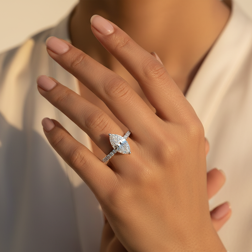 Generated fresh lifestyle variation - Indian female model wearing the white gold marquise-cut diamond solitaire ring with large round brilliant diamond pavé shank, direct overhead top-down angle warm golden hour light on ivory background with delicate blush styling