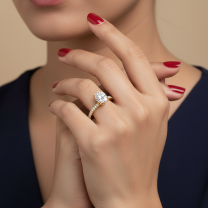 Generated image of a beautiful Indian female model wearing the yellow gold oval-cut diamond solitaire engagement ring with four-claw setting, delicate hidden under-halo of small round brilliant diamonds beneath the basket, and elegant pavé diamond shank