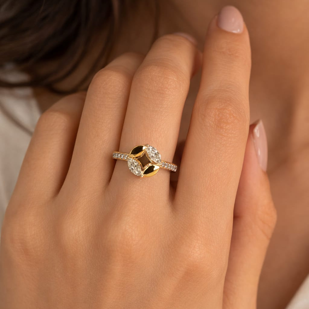 Close-up of a hand wearing a gold and diamond ring against a neutral background