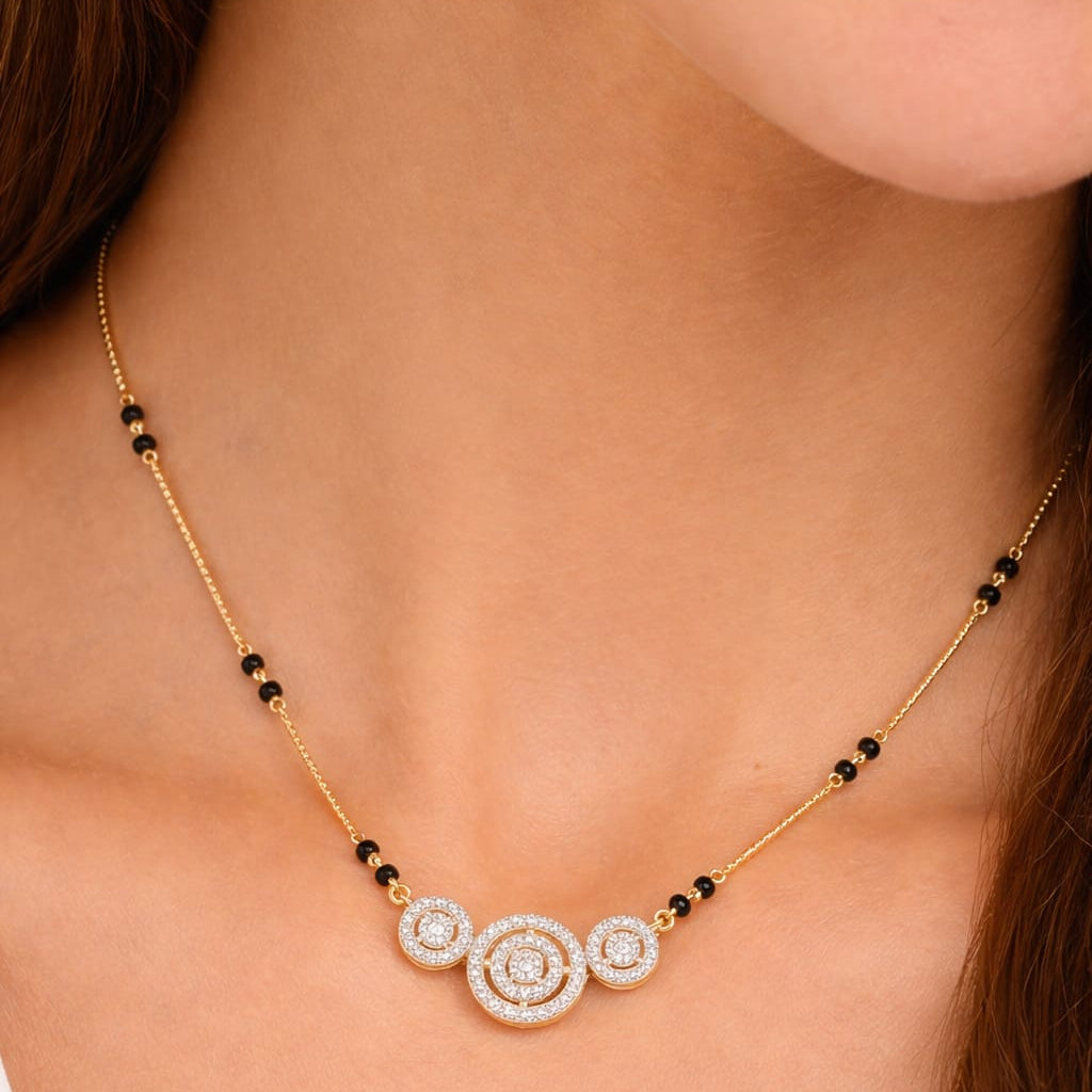 Gold necklace with black beads and circular pendant on a person's neck