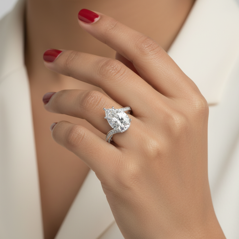 Generated image of an Indian female model wearing the white gold five-claw pear-cut diamond solitaire with spectacular split-shank pavé diamond rails sweeping elegantly apart in a dramatic sculptural embrace