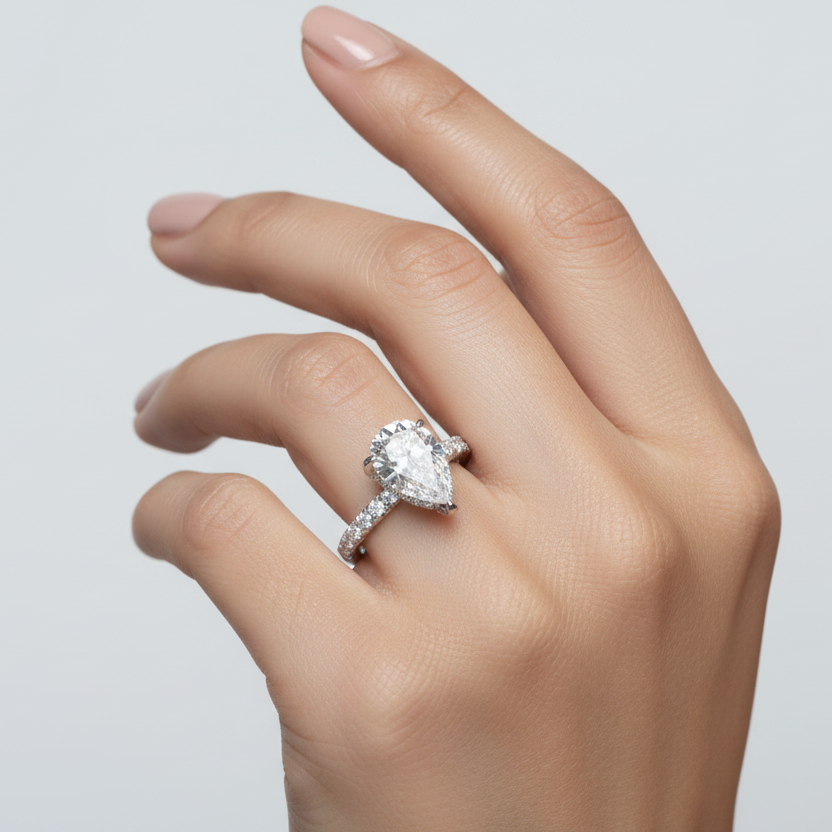 Generated image of an Indian female model wearing the white gold five-prong pear-cut diamond solitaire engagement ring with hidden micro-pavé halo under-gallery and pavé diamond band