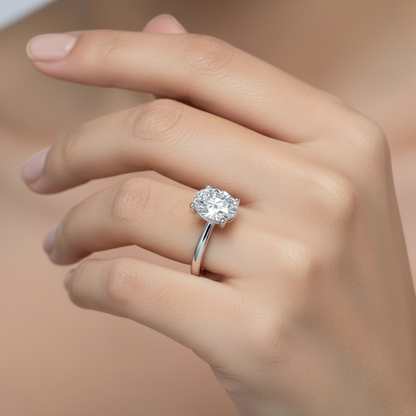 Generated image of an Indian female model wearing the white gold four-prong oval brilliant solitaire engagement ring on a wide plain polished comfort-fit band