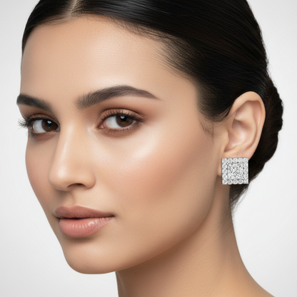 Generated image of an Indian female model wearing the white gold four-prong princess-cut diamond solitaire stud earrings with bold square round brilliant diamond halo
