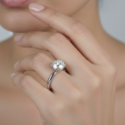Generated image of an Indian female model wearing the white gold four-prong round brilliant solitaire engagement ring on a wide plain polished comfort-fit band