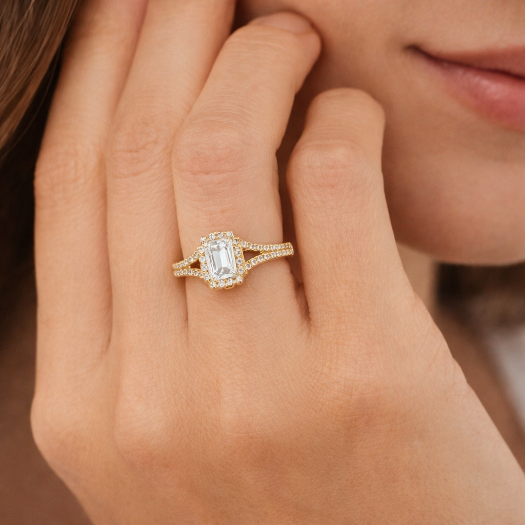 Close-up of a hand wearing a gold ring with a diamond on a blurred background