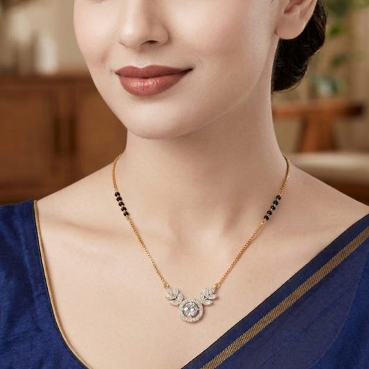 Woman wearing a gold necklace with a blue top in a blurred indoor setting