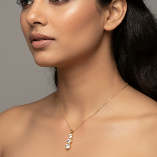 Generated image of an Indian female model wearing the yellow gold three-stone graduating round brilliant diamond drop pendant necklace