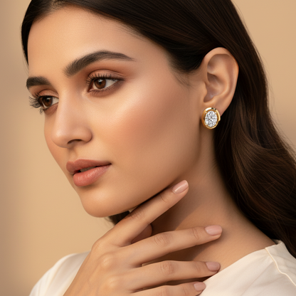 Generated very small dainty size variation - beautiful Indian female model wearing the yellow gold oval-cut diamond solitaire stud earrings with wide flat oval bezel frame as extremely tiny delicate petite accent studs, warm golden hour light on champagne background with soft romantic waves hairstyle and ivory silk outfit