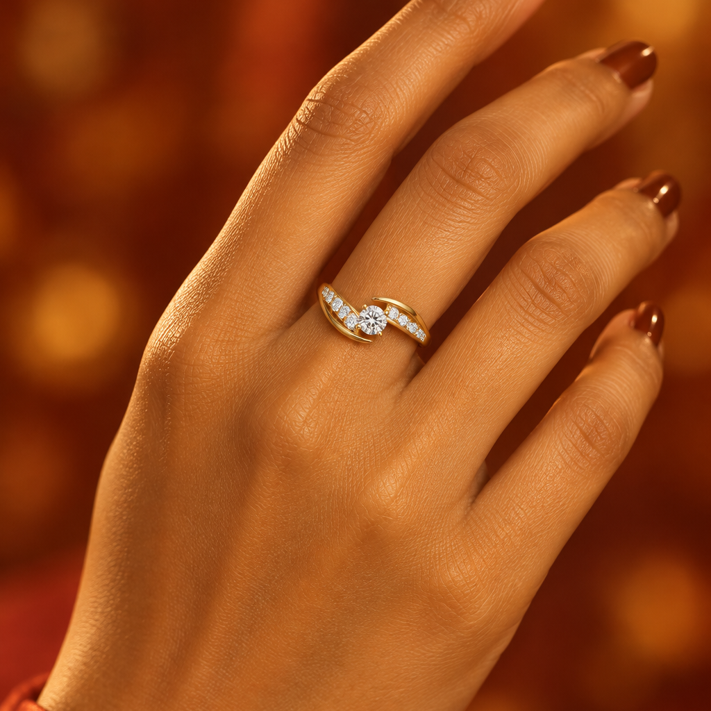 Indian female model's hand with warm golden skin and deep rich cognac warm caramel brown manicure wearing a very small yellow gold round brilliant diamond solitaire ring with a dramatic diagonal crossover bypass diamond band — band splitting into two sweeping diagonal arms crossing past each other in opposite directions around the center stone both arms channel-set with round brilliant diamonds running diagonally; center round brilliant diamond in a four-prong yellow gold tension-style setting held between 