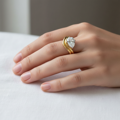 Two-tone gold pear-shaped diamond solitaire ring with curved chevron band on model